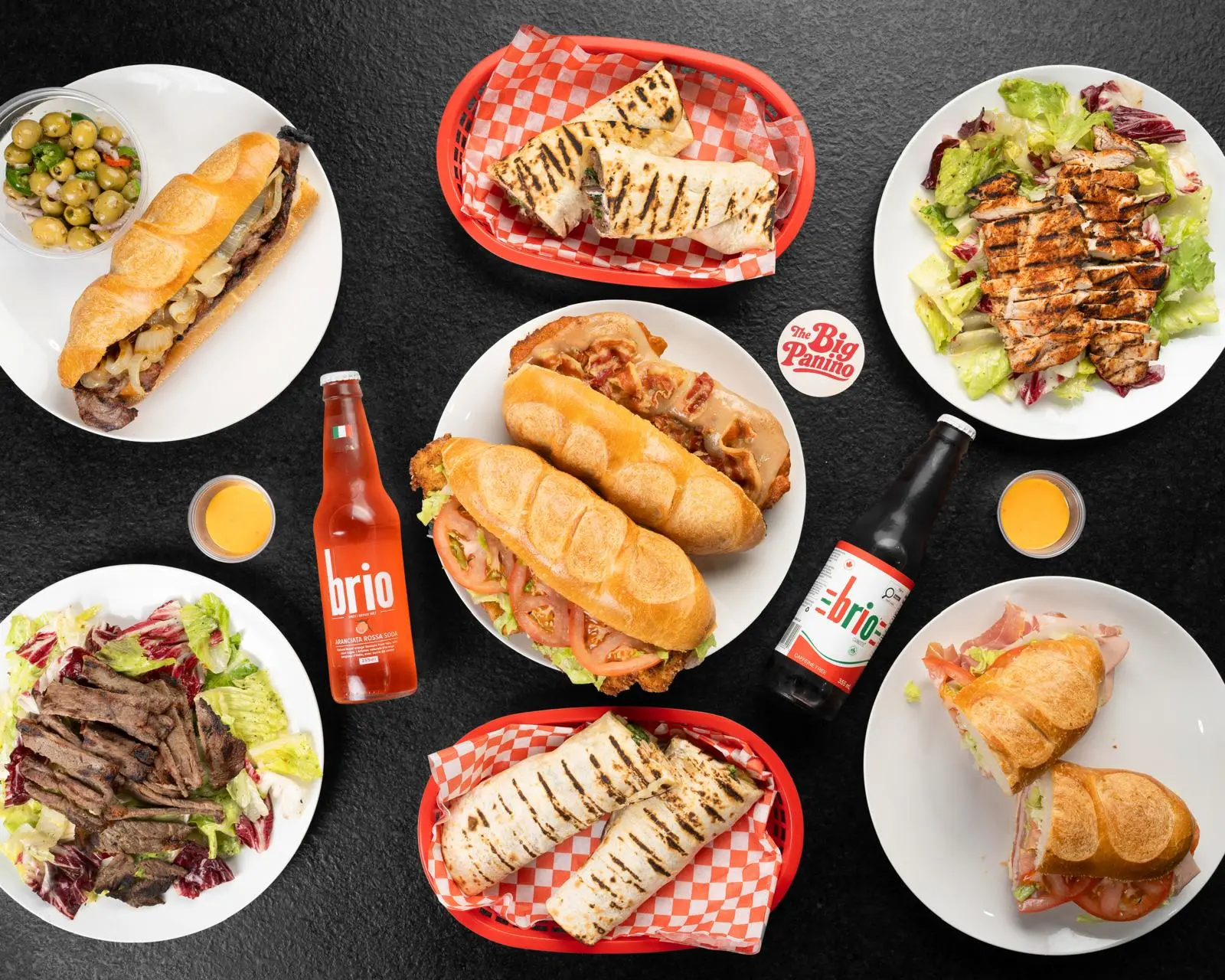 Spread of Big Panino hoagies, paninos, wraps, salads and marinated olives